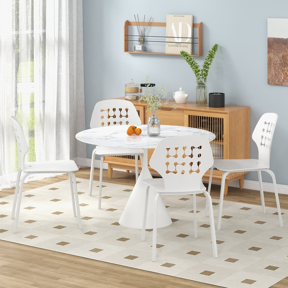 Four white metal dining chairs placed around a dining table in a bright room