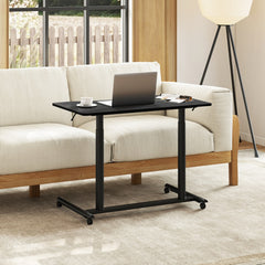 The office desk positioned in front of a sofa with a laptop and a cup of tea on the surface