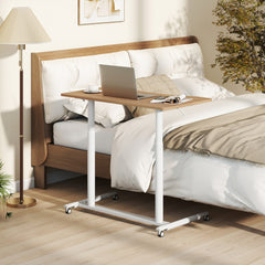 The adjustable height desk beside a bed with a laptop on it