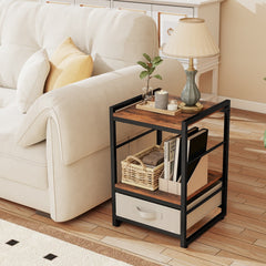 The bedside table holding a lamp and books next to a sofa with a fabric drawer at the base
