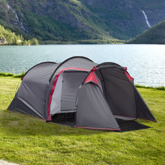 The grey camping tent is set up on a grassy area next to a body of water with hills in the background