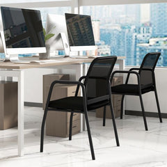 Two black office chairs placed next to a desk with computers in a modern office setting