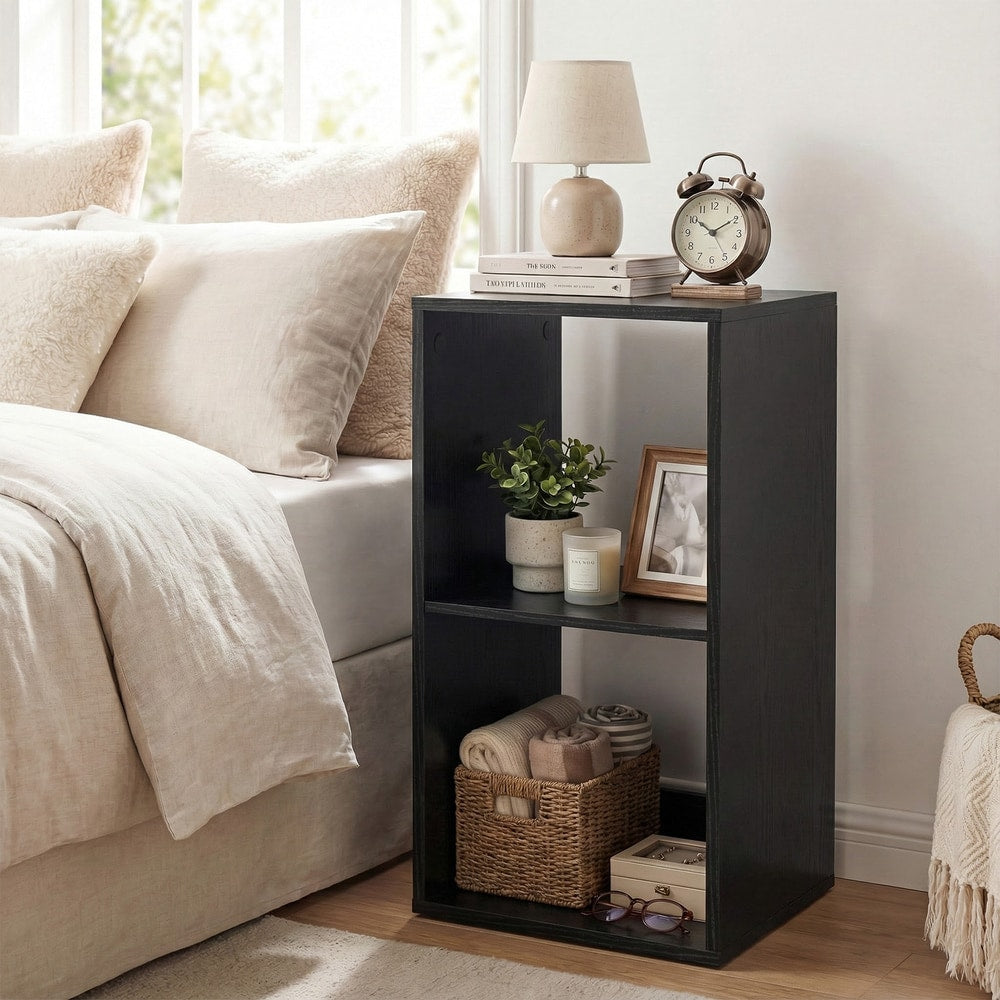 The black two-tier bookcase used as a bedside table with a lamp and books on top