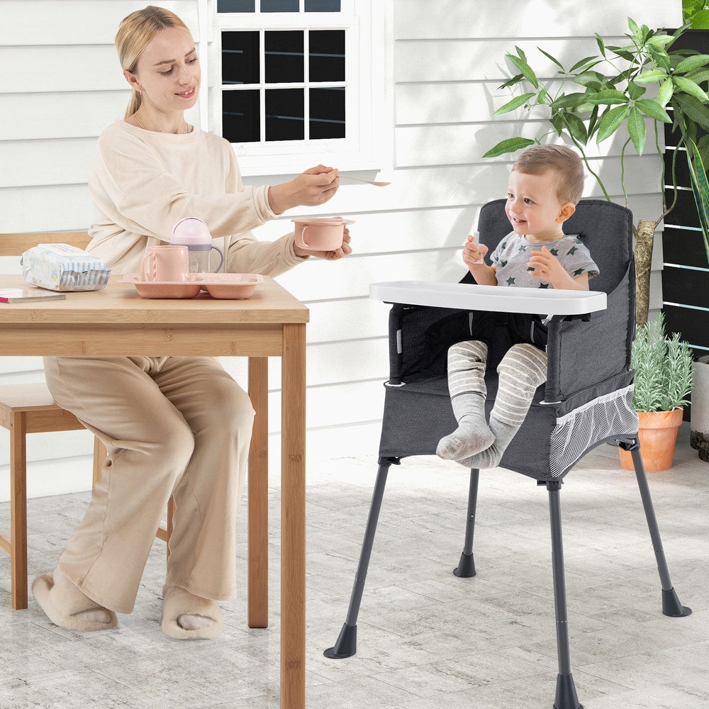 The feeding chair in use by a toddler sitting at a table on a patio with a woman