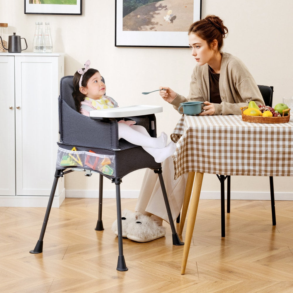 The feeding chair positioned at a dining table with a child sitting inside
