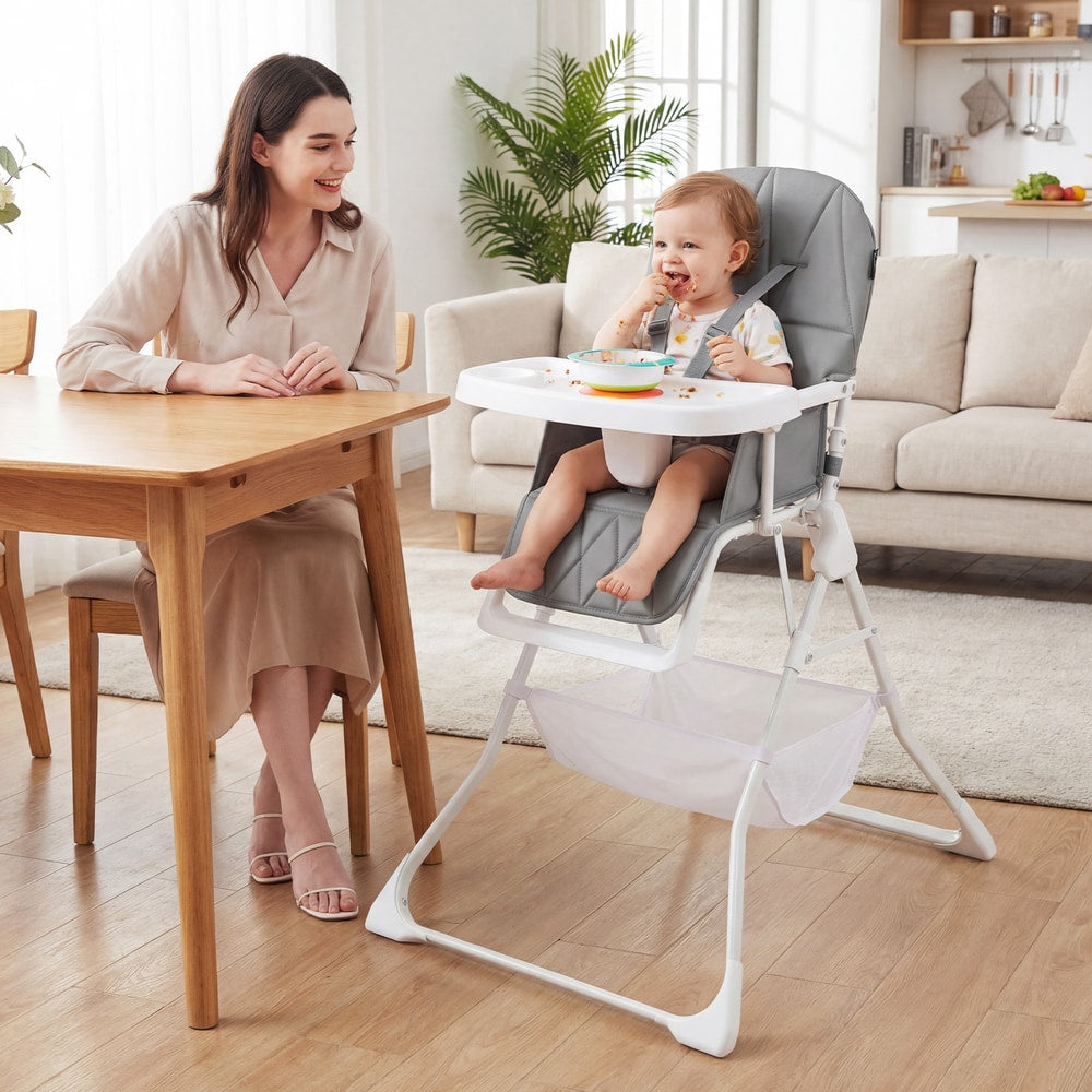 A mother smiles at her baby sitting in the grey portable high chair at a dining table