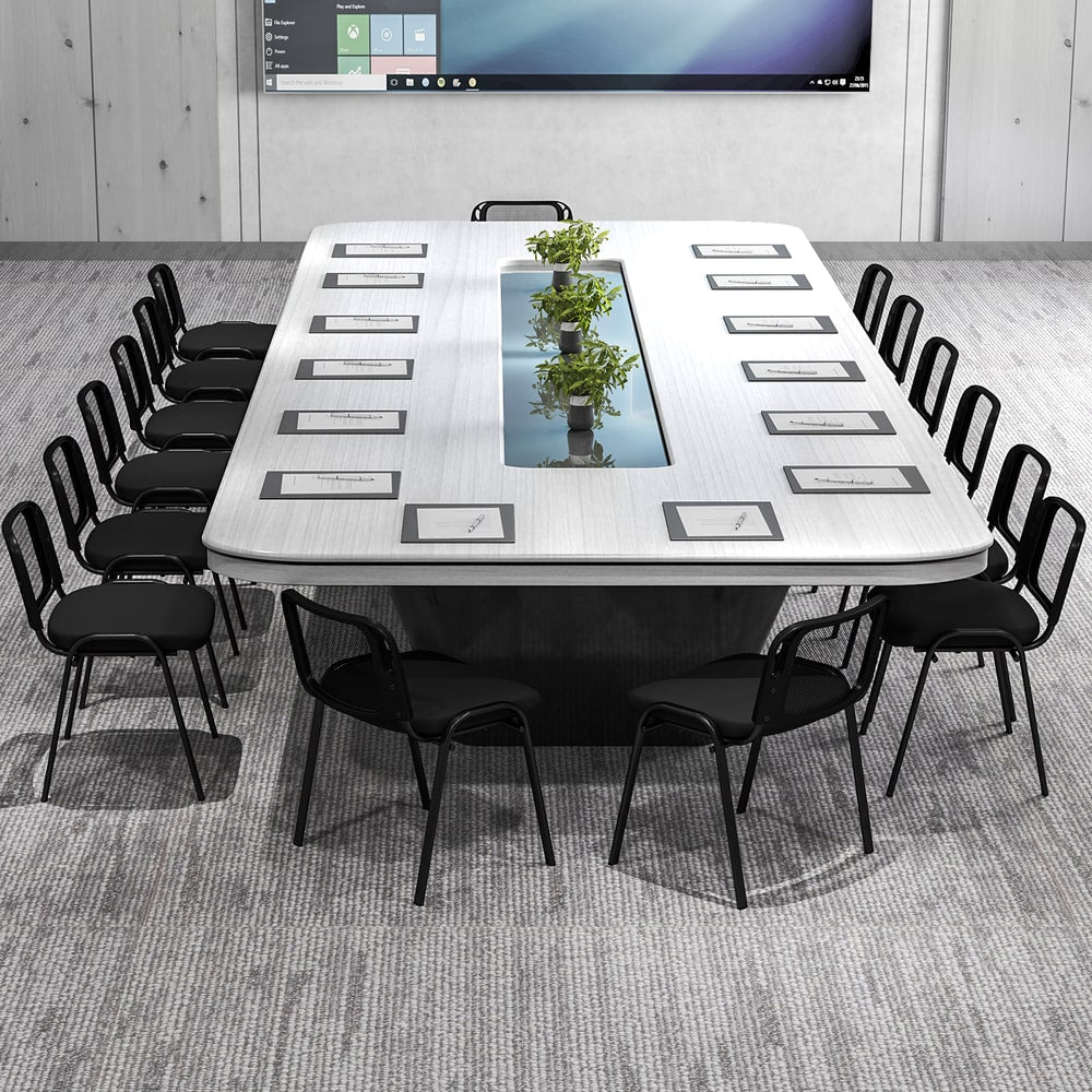 The office chairs set around a long white boardroom table with a central glass feature