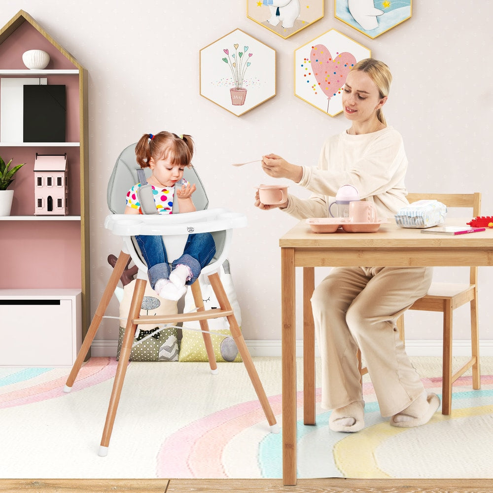 A mother feeding her baby in the wooden baby infant high chair in a dining room