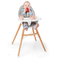 A baby sitting in the wooden baby infant high chair eating an apple
