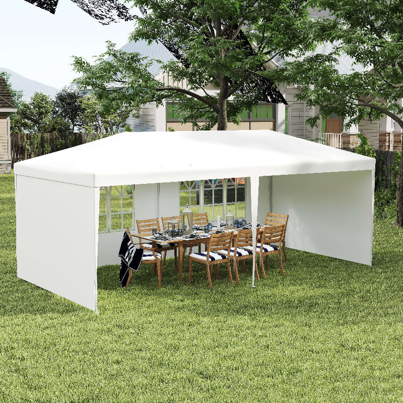 White outdoor canopy set up over a dining area with chairs and a table on a grassy lawn.