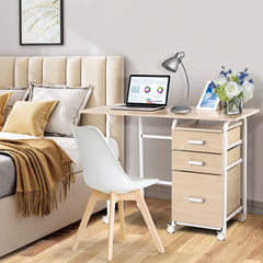 The office desk is set up in a bedroom next to a bed with a white chair in front