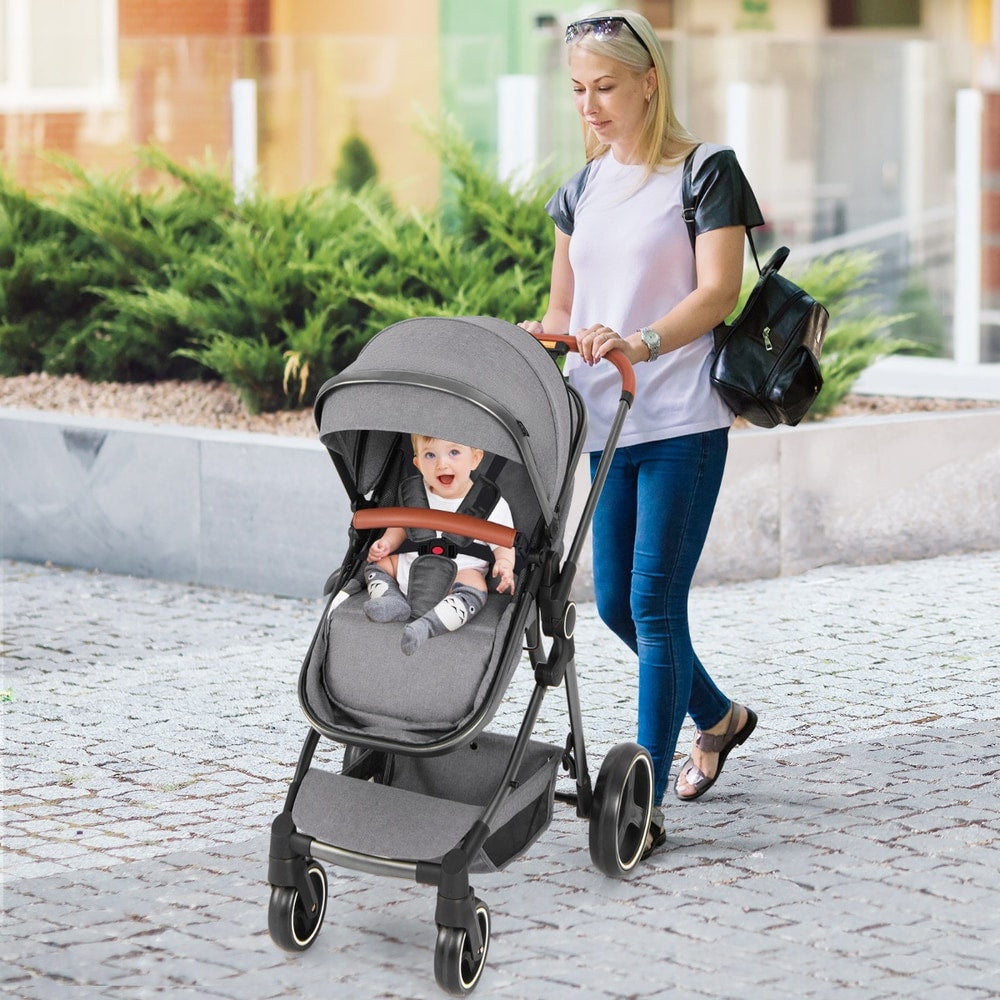 A woman pushing the grey baby stroller with a baby inside on a pavement