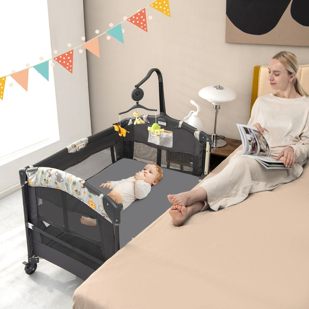 The bedside sleeper positioned next to a bed with a baby lying inside while a woman reads