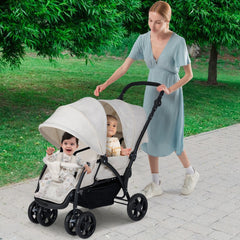 A beige double pushchair with two children seated, with a woman pushing it on a paved path