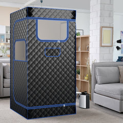 The portable steam sauna in a modern living room setting next to a sofa and shelving unit