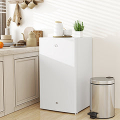 The compact white under-counter fridge in a kitchen setting next to a bin and countertop items