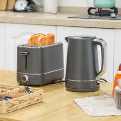 The kettle and toaster set in a kitchen setting with toast in the toaster and water boiling in the kettle