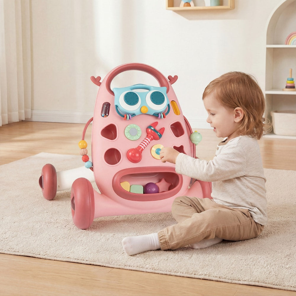 A baby sits and plays with the shape sorter and other interactive features on the pink baby walker