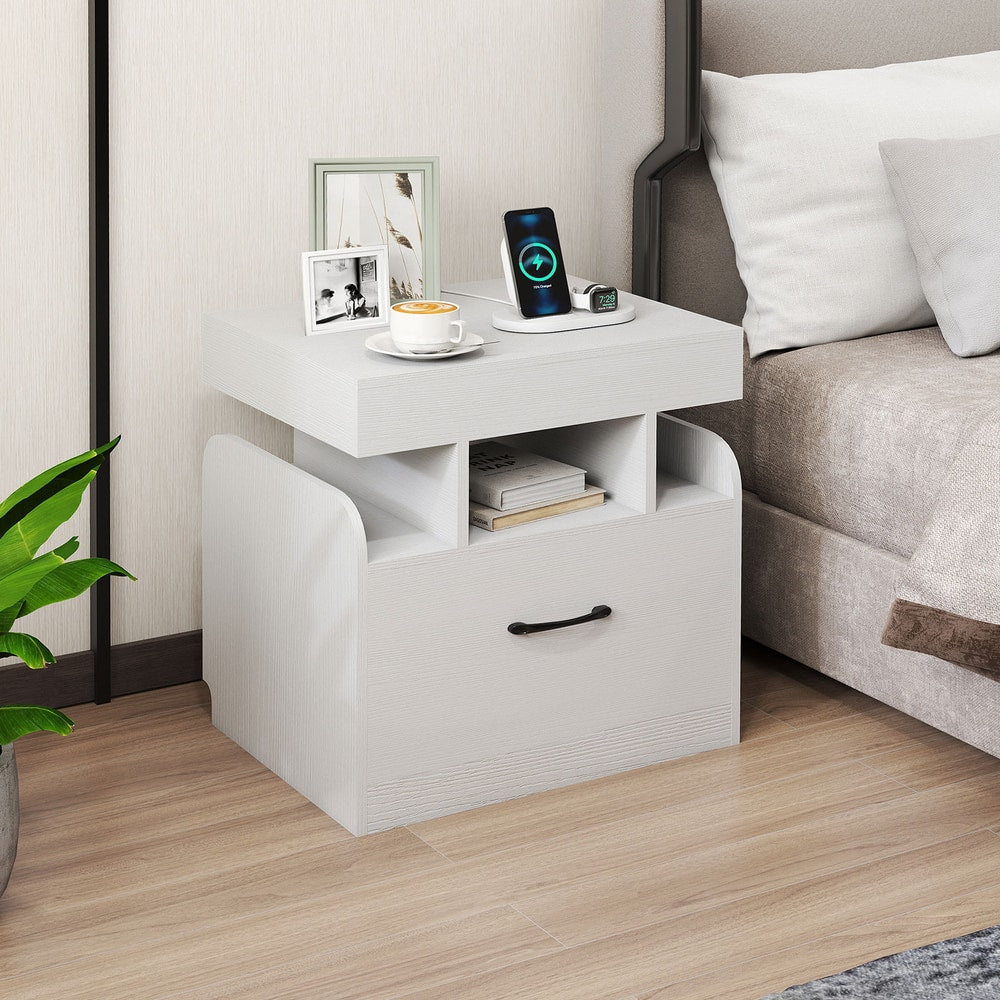 White bedside table with drawer and open shelf next to a bed