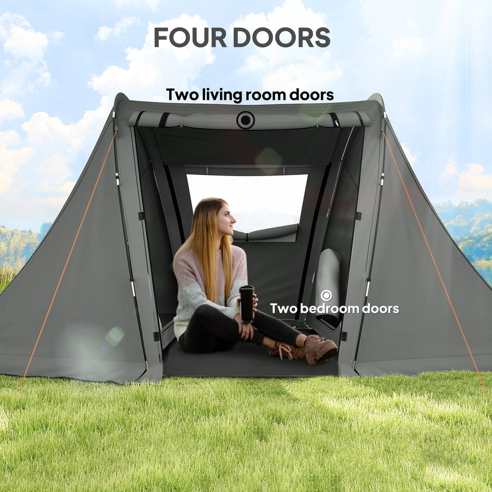 A woman sitting inside a grey three man camping tent with four doors, showing the living and bedroom areas