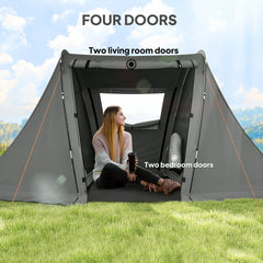 A woman sitting inside a grey three man camping tent with four doors, showing the living and bedroom areas