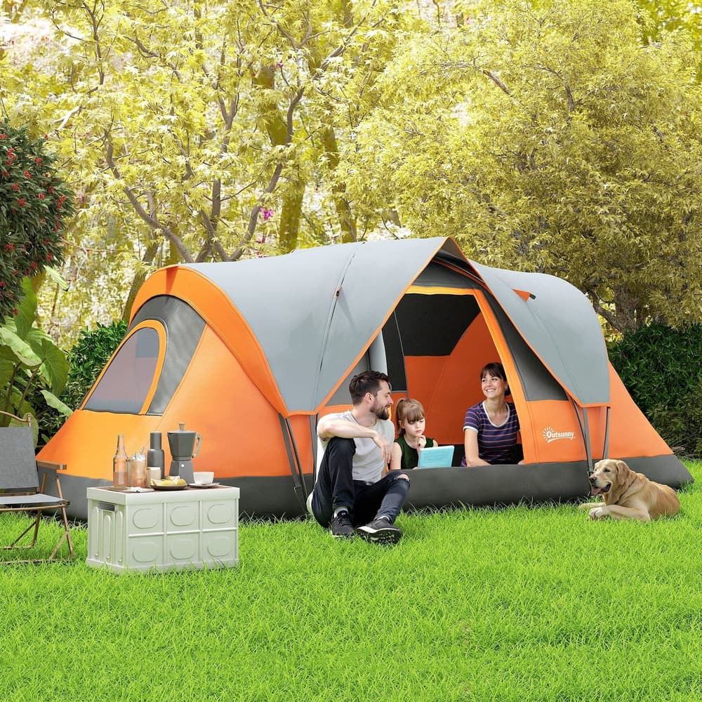 A family and a dog relaxing inside the orange and grey dome camping tent pitched on grass