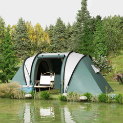 The camping tent set up next to a lake with camping chairs and a cooler box nearby