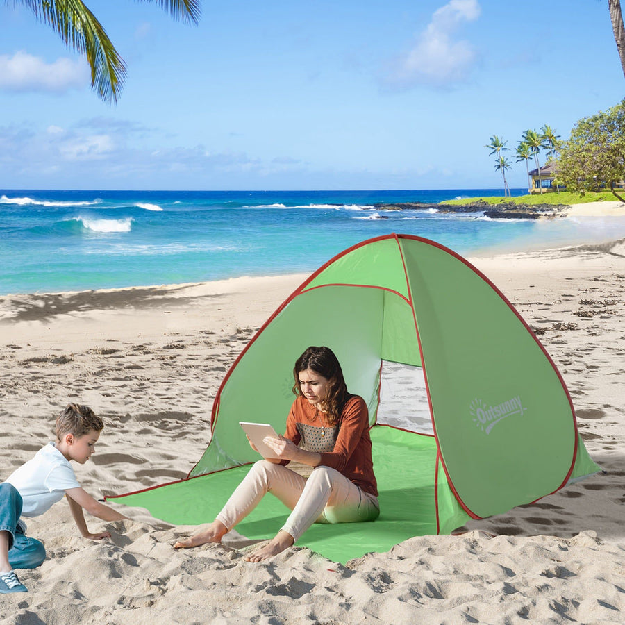 Outsunny Pop Up Tent set up on a sandy beach with a woman and child sitting inside