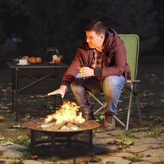 Man sitting by a campfire in a green padded camping chair