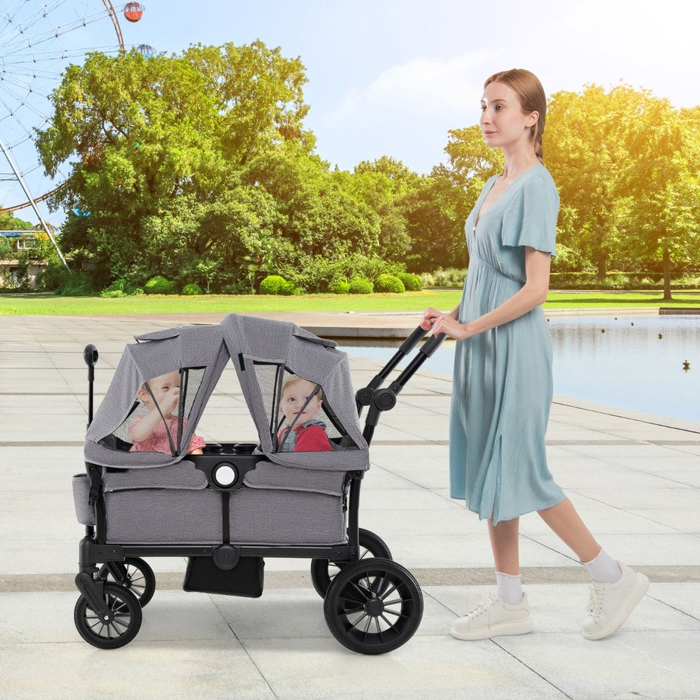 The baby stroller being pushed by a woman with two children under the canopy