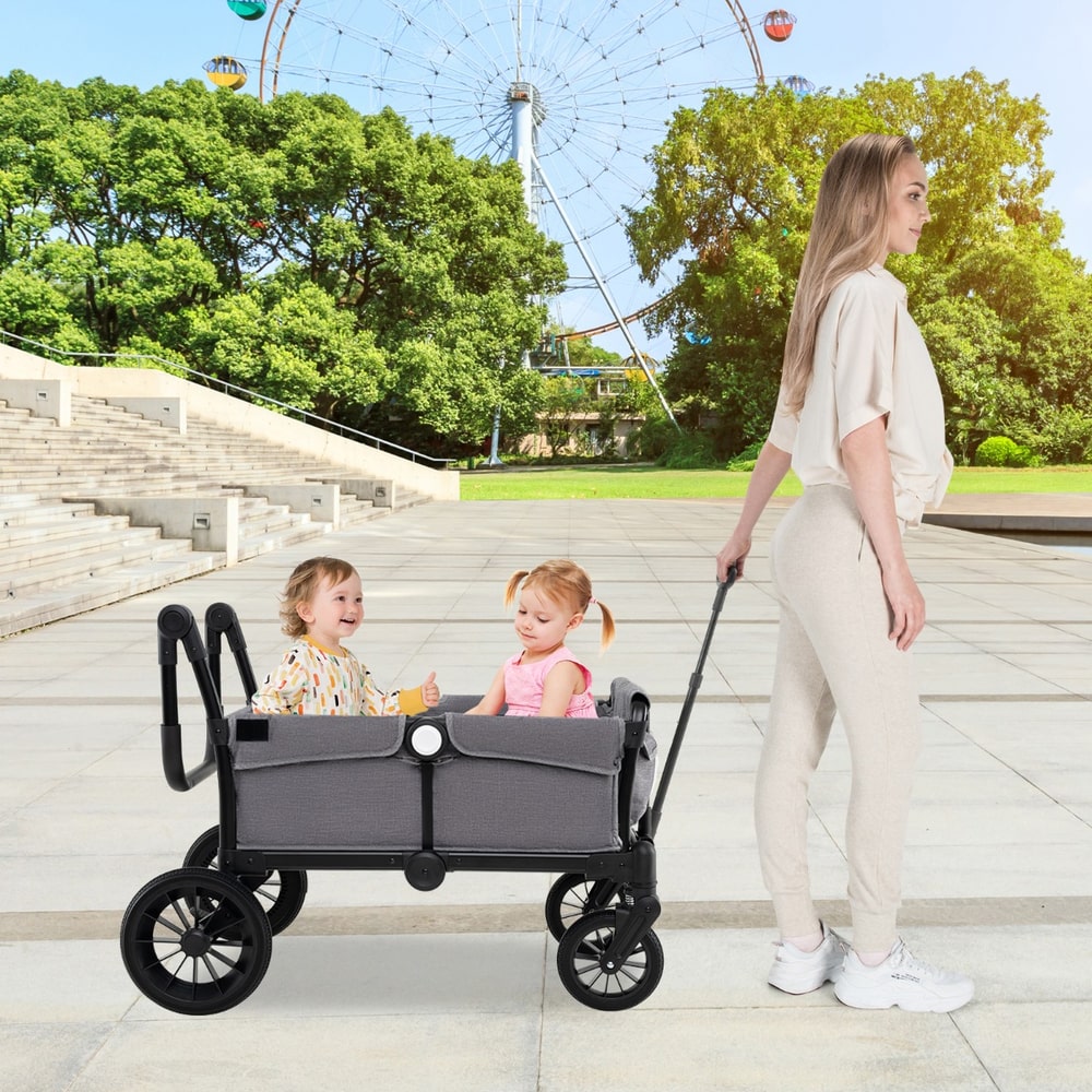 The baby stroller being pulled by a woman with two children sitting inside